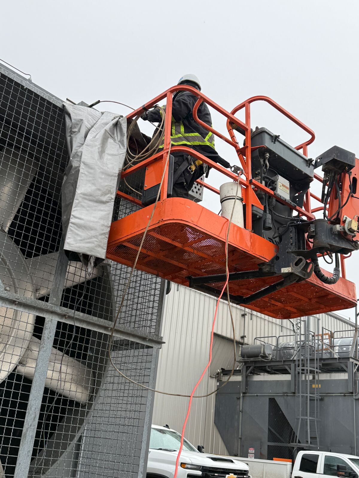 AIT technician performing elevated inspection from an articulated boom lift on a cooling tower fan stack