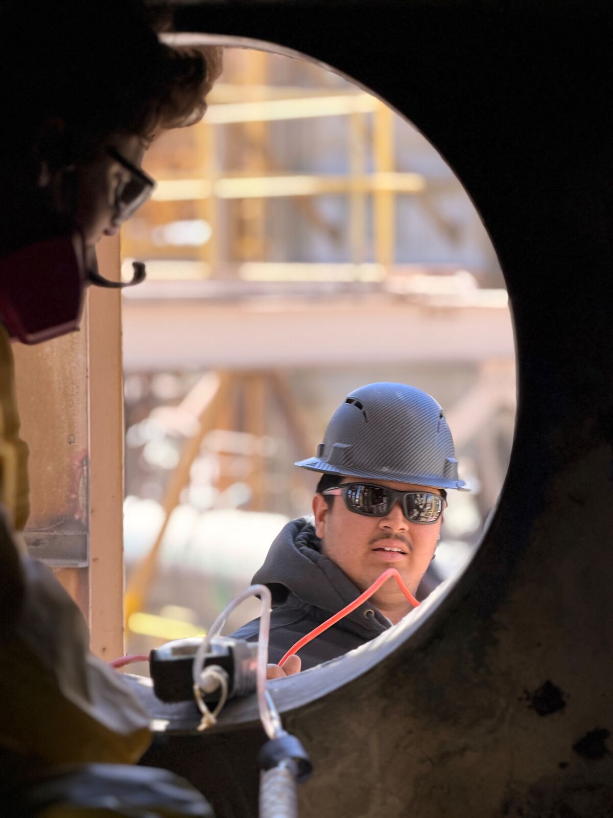 AIT inspectors coordinating inside a confined-space vessel manway with hardwired comms
