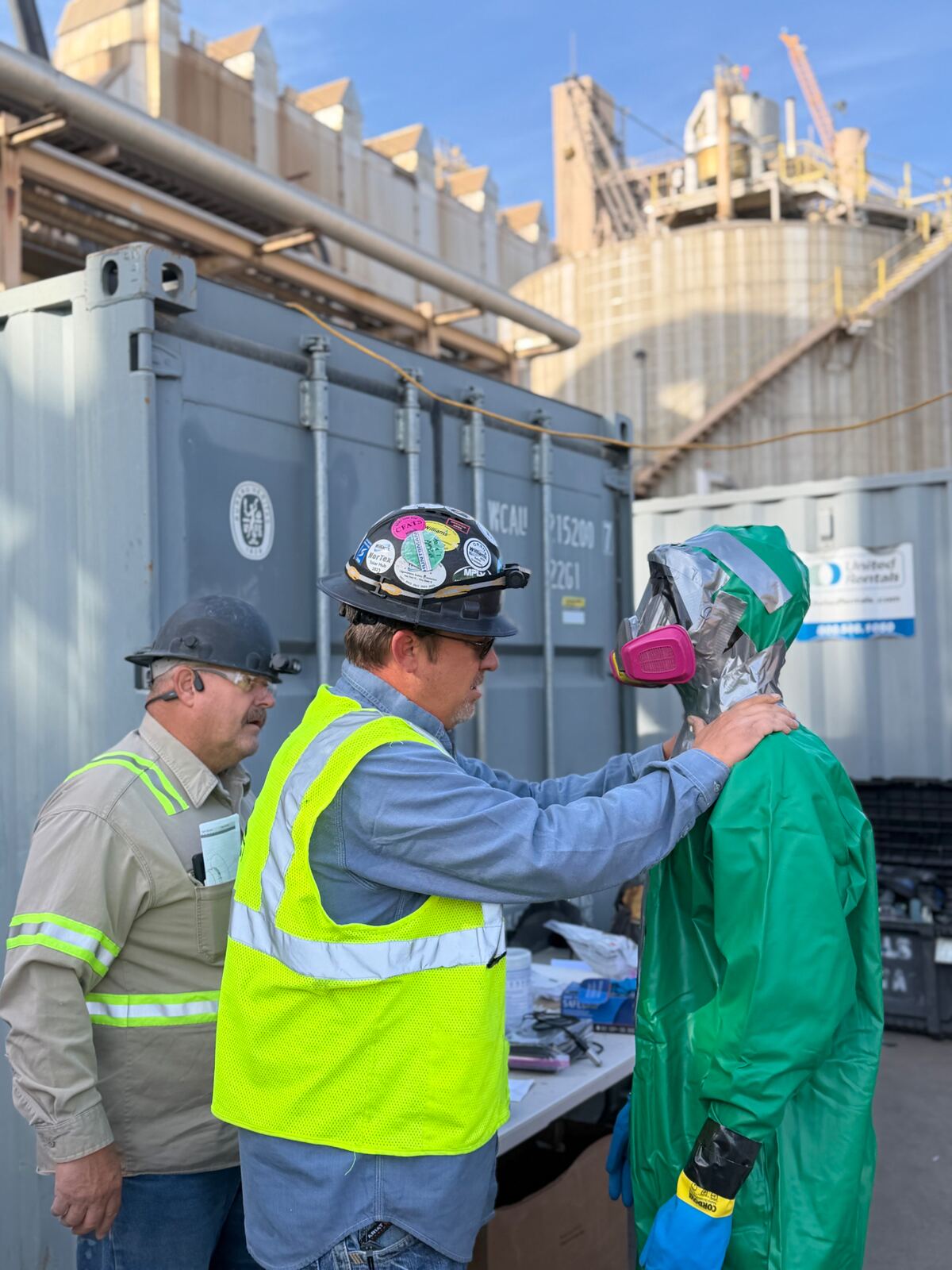AIT field team conducting pre-job PPE check at an industrial facility laydown area